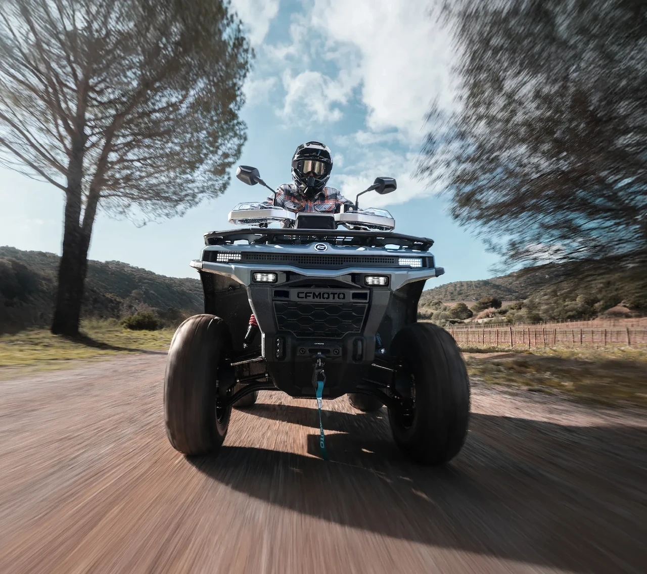 2027 CFMOTO CFORCE C4 ATV viewed from the front with a helmeted rider on a dirt trail.