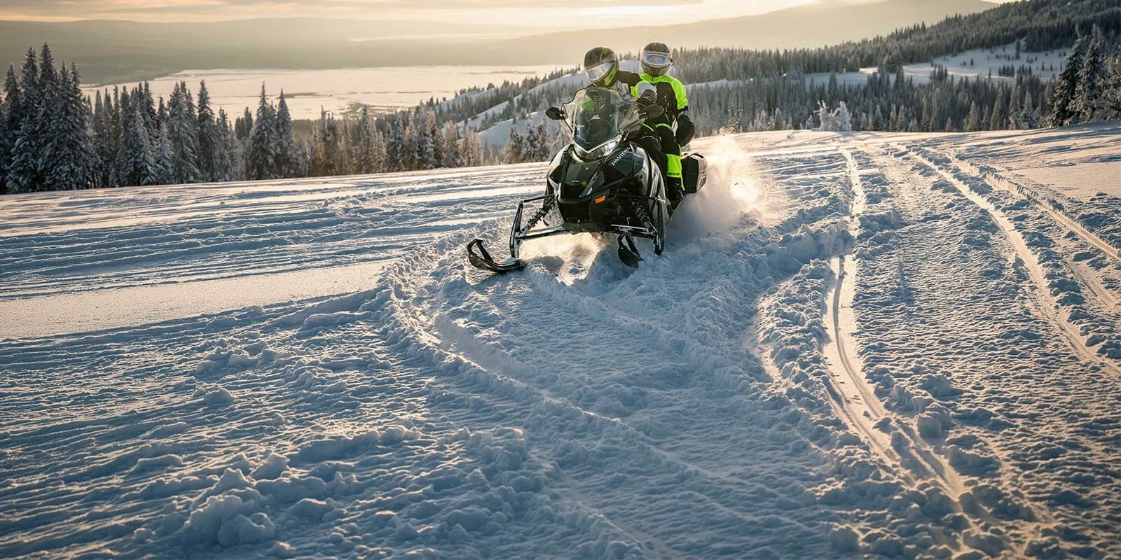 2027 Arctic Cat Pantera 9000 touring snowmobile with two occupants on a snowy trail.