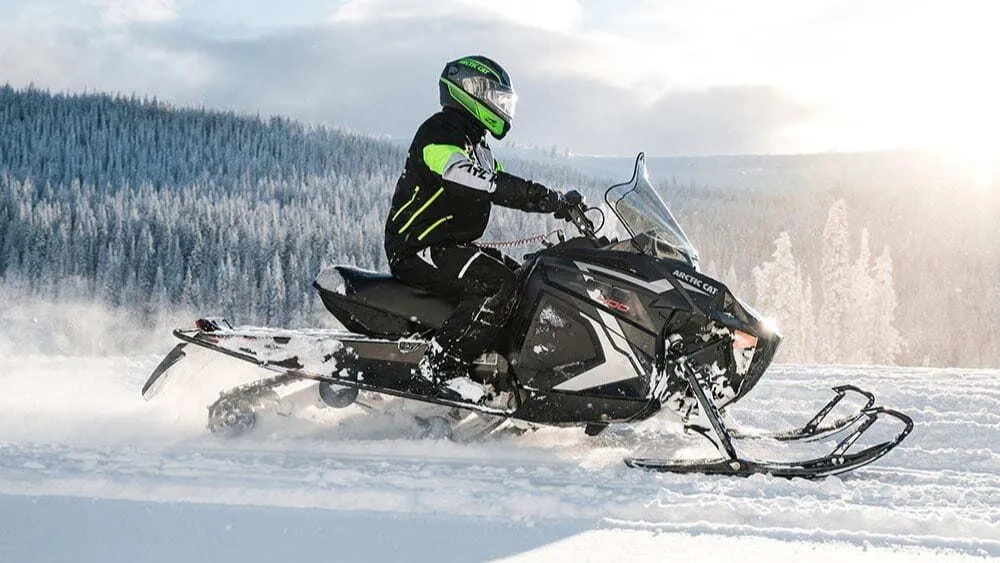 2027 Arctic Cat Jag 400 trail snowmobile being ridden on a snowy trail.