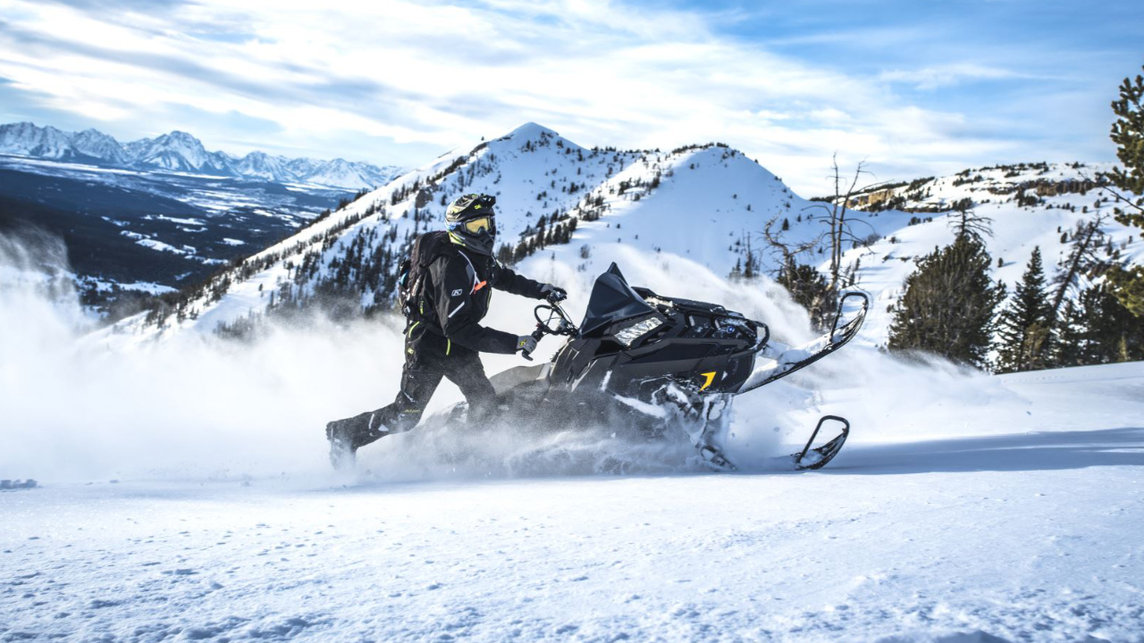 man on a Polaris snowmobile in the mountains