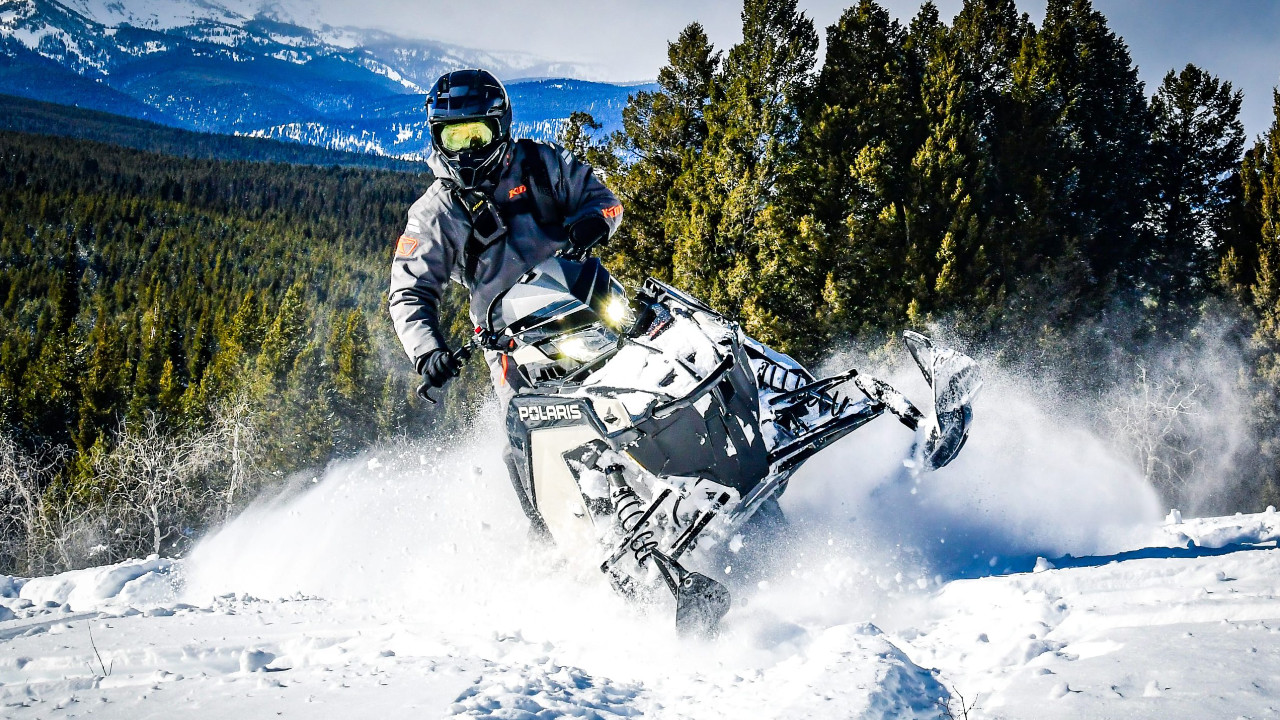 man on a Polaris snowmobile on a snowy mountain