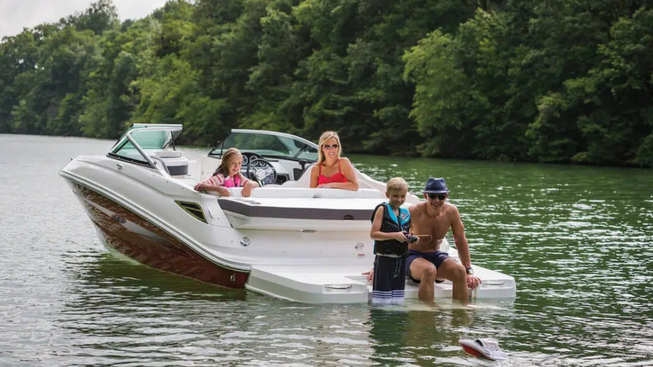 jeune garçon à bord d'un bateau avec sa famille en train de jouer avec un petit bateau téléguidé