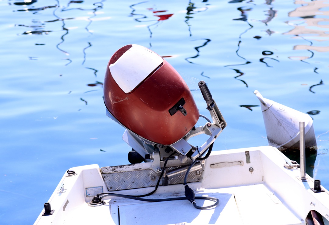Gros plan d'un moteur à hélice d'un hors-bord sur des eaux calmes.