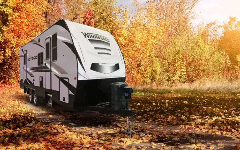 vue latérale avant d'un Winnebago Voyage en forêt l'automne