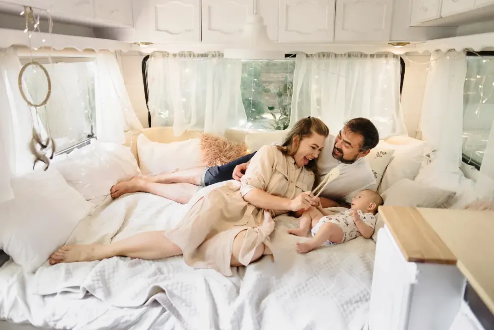 Un couple et leur bébé sur le lit d'une roulotte.