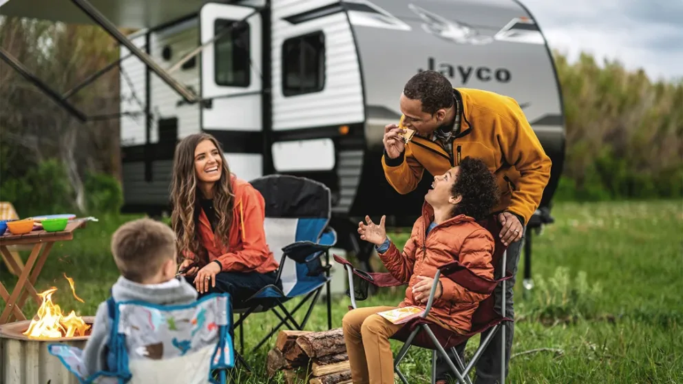 Famille en camping avec une roulotte Jayco en arrière-plan.