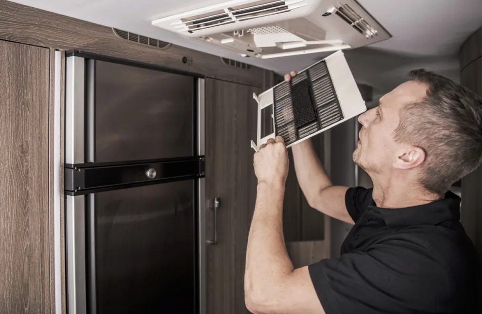 Un homme qui nettoie les filtres de ventilation.