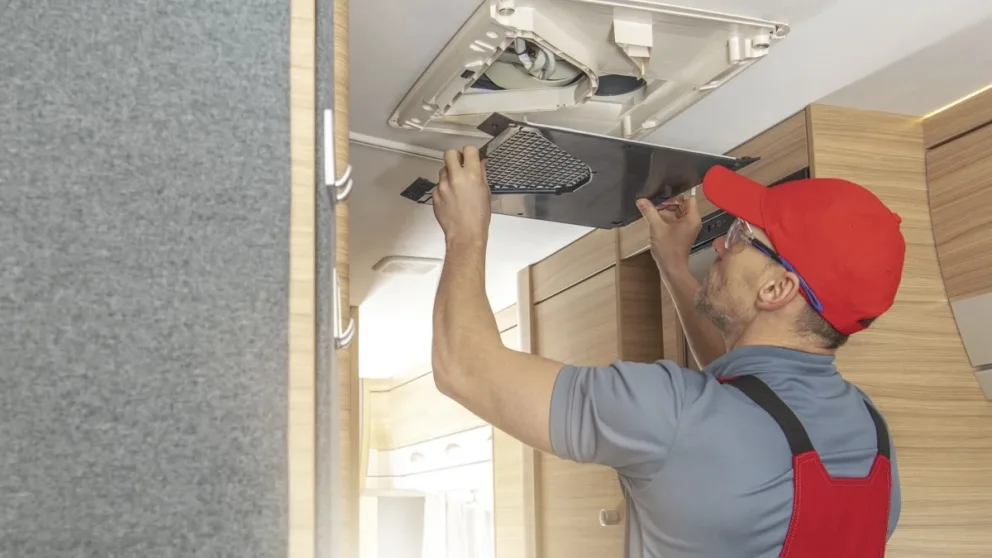 Un homme qui répare la ventilation d'une roulotte.