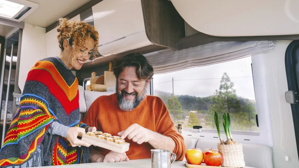 Une femme qui propose à son mari des biscuit à bord de leur VR.