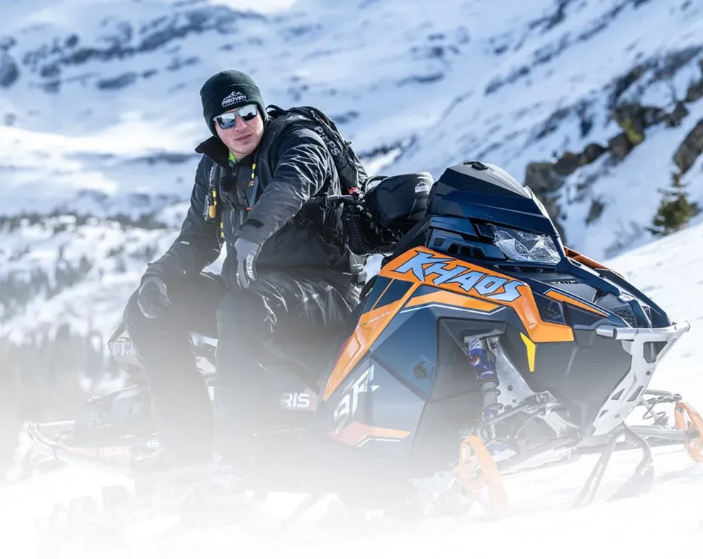 Motoneige Polaris RMK Khaos Limited Edition 2026 escaladant une pente enneigée en montagne, vue latérale dynamique.