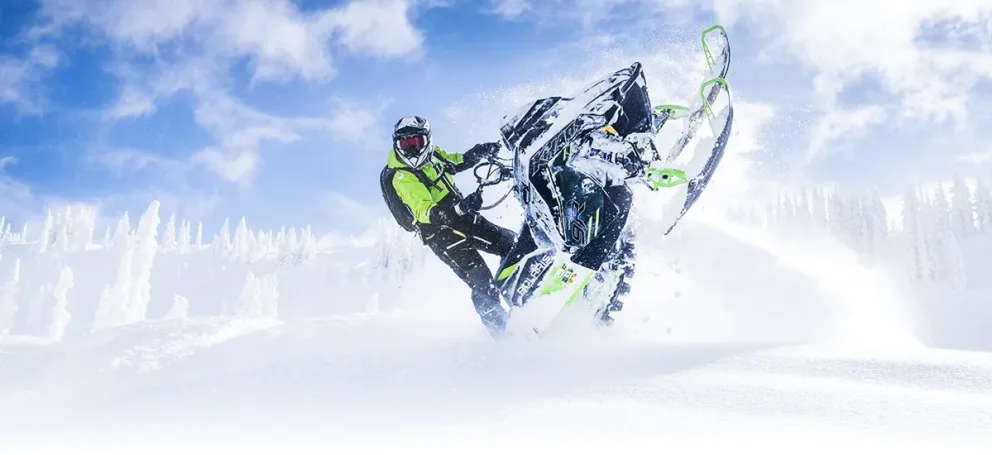 Motoneige Polaris RMK Khaos 2026 noire avec accents verts effectuant une manœuvre de wheely dans la poudreuse.