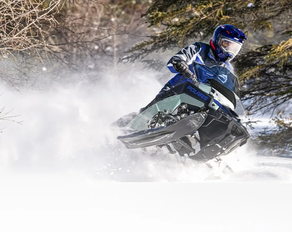 Motoneige Polaris Switchback Sport 2026 noire et blanche en déplacement dans la neige profonde.
